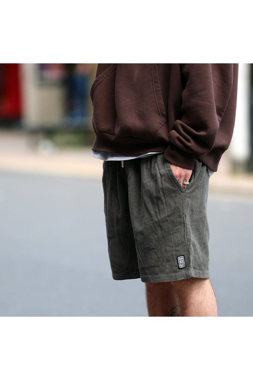 Bamboobay cord shorts in olive green with hands in pockets side view